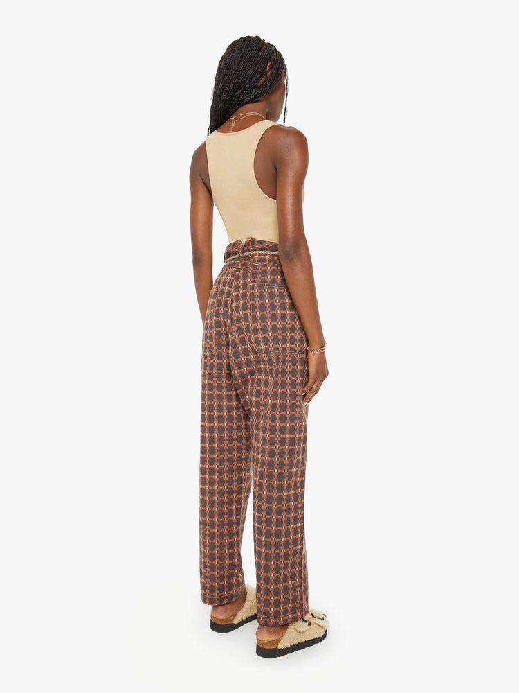 Back view of a woman farmer pant in an orange and brown print with a high rise, straight leg, drawstring waist, a slightly cropped inseam and a loose fit.