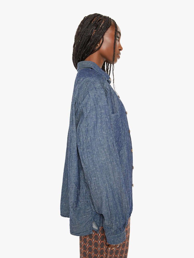 Side view of a woman blue shirt with ront patch pockets, buttons down the front and a boxy, oversized fit.
