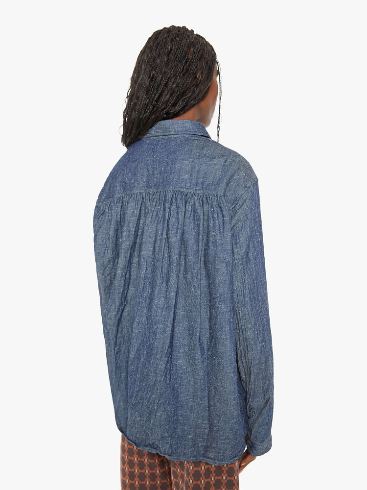 Back view of a woman blue shirt with ront patch pockets, buttons down the front and a boxy, oversized fit.