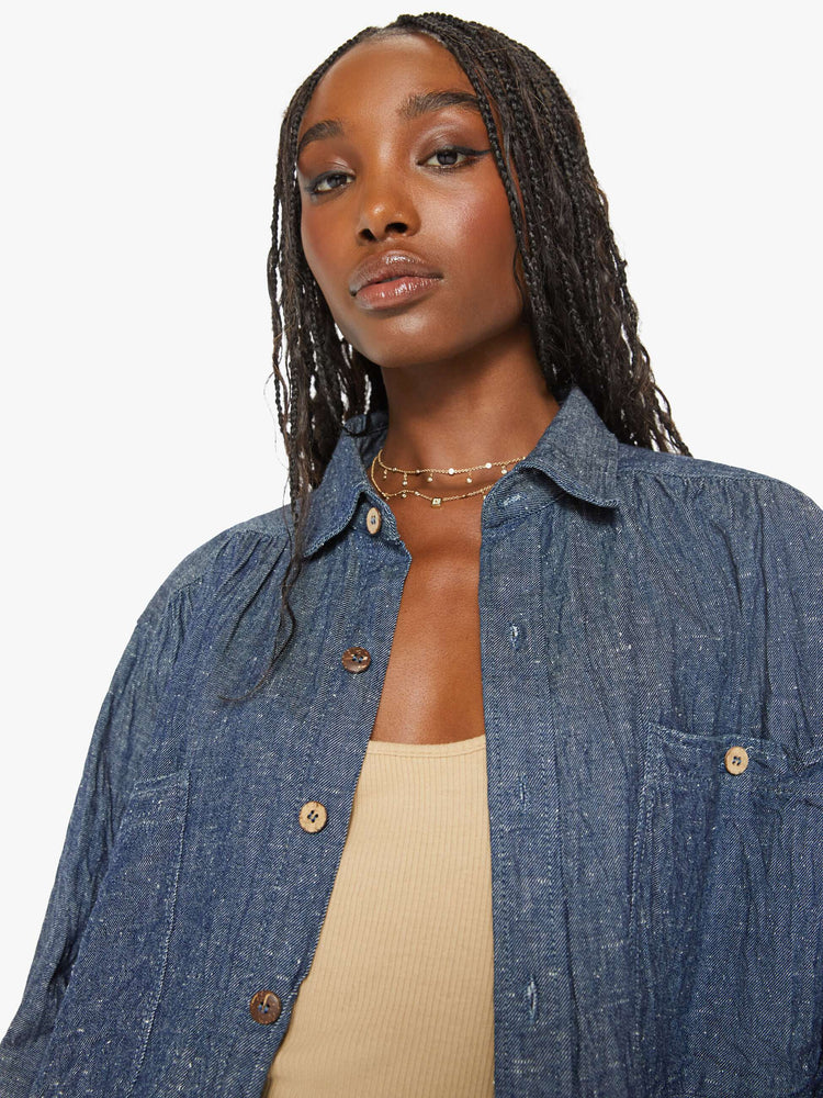 Close up view of a woman blue shirt with ront patch pockets, buttons down the front and a boxy, oversized fit.