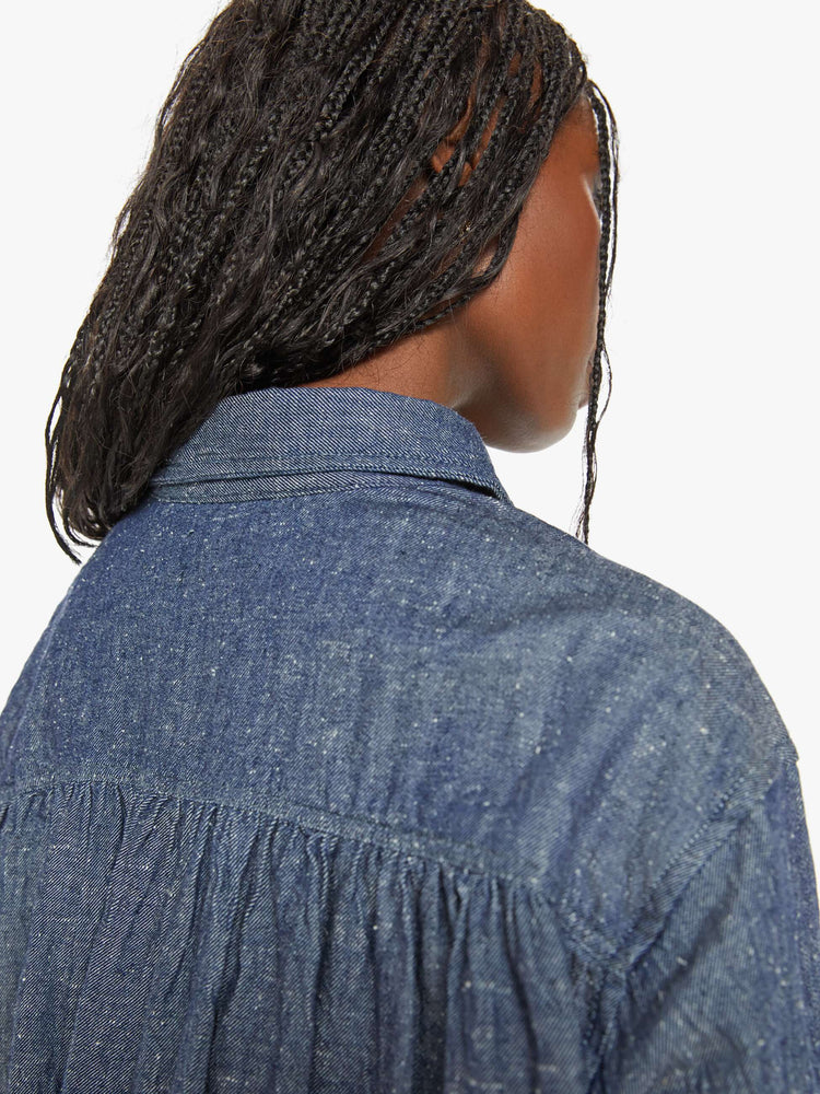 Back close up view of a woman blue shirt with ront patch pockets, buttons down the front and a boxy, oversized fit.