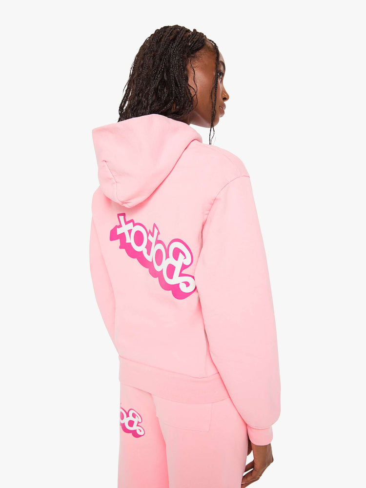 Back view of a woman sweatshirt in baby pink has a front patch pocket, ribbed hems and a slightly oversized fit with a two-toned text graphic on the front.