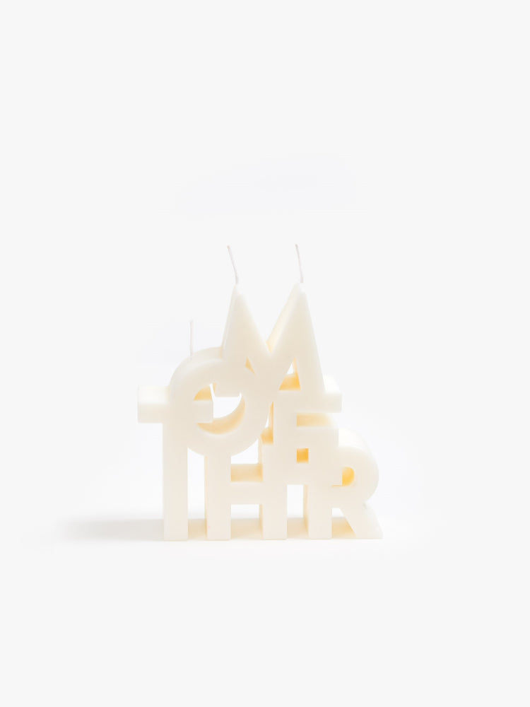 Image of an off white candles made up of stacked letters reading "MOTHER".