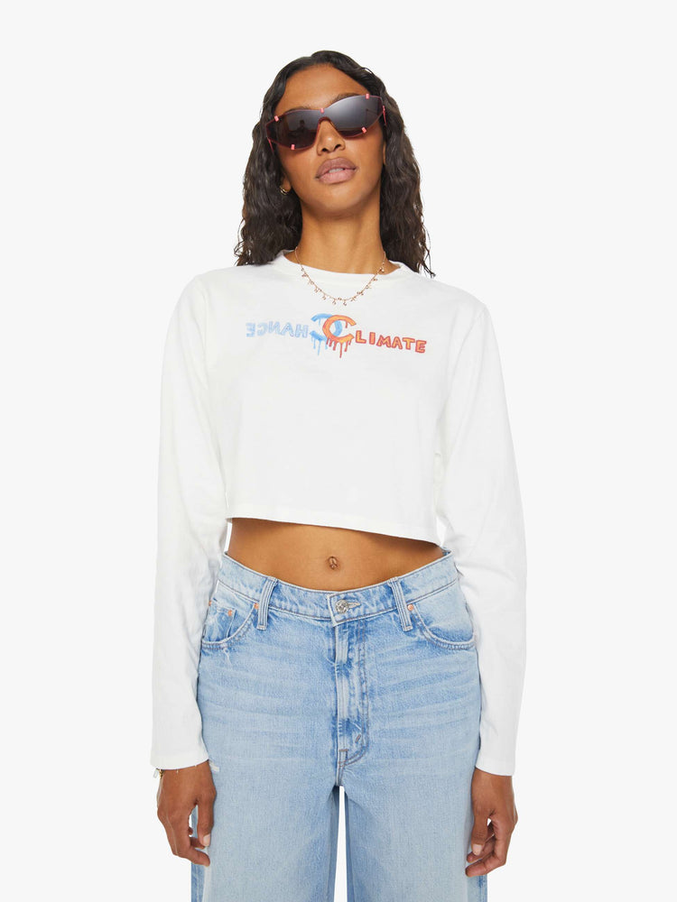 Front view of a woman long sleeve tee is designed with a crew neck, drop shoulders, cropped hem and a slightly oversized fit in white and features a colorful hand-drawn text graphic.