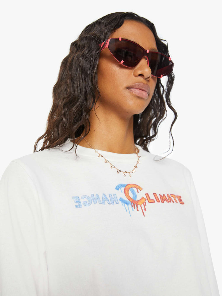 Close up view of a woman long sleeve tee is designed with a crew neck, drop shoulders, cropped hem and a slightly oversized fit in white and features a colorful hand-drawn text graphic.