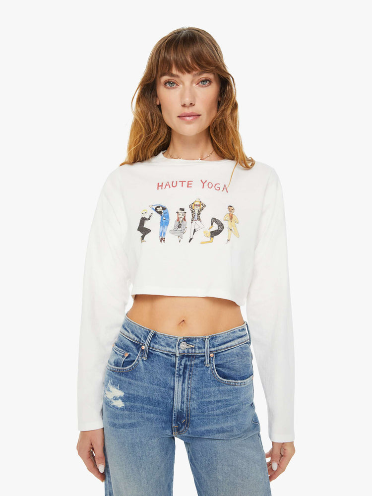 Front view of a woman long sleeve tee with a crew neck, drop shoulders, a cropped hem and a slightly oversized fit  in white and features a colorful hand-drawn text graphic that reimagines the concept of hot yoga.
