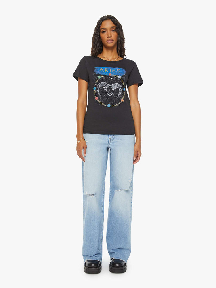 Full body view of a woman black tee features a colorful, hand-drawn graphic depicting the Aries ram.