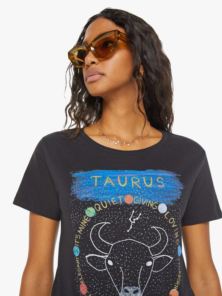 Close up view of a woman black tee eatures a colorful, hand-drawn graphic depicting the Taurus bull, the earthly second astrological sign in the zodiac.