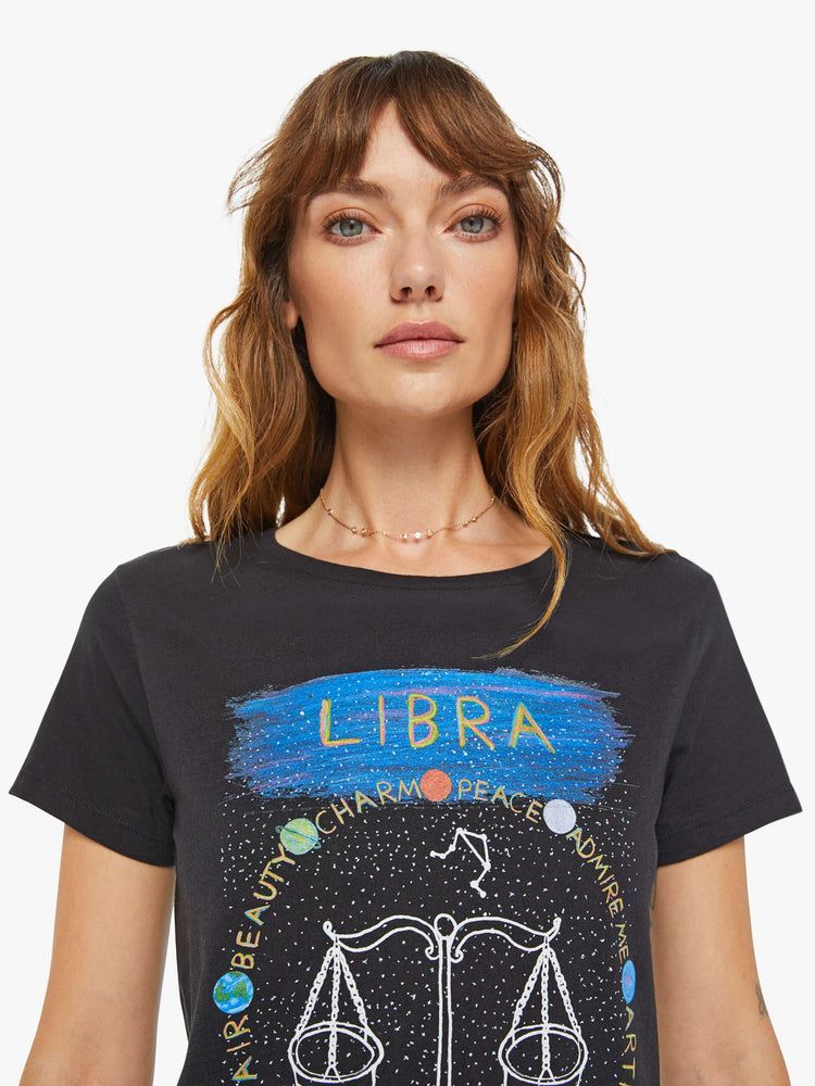 Close up view of a woman black tee features the Libra scale, the seventh astrological sign in the zodiac.