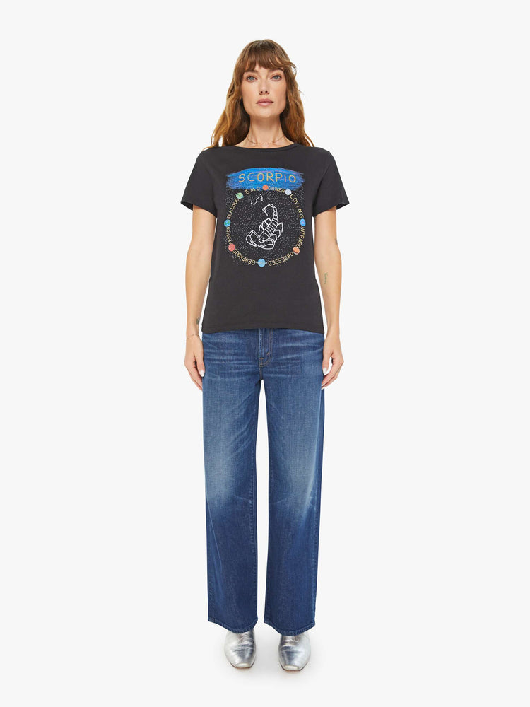 Full body view of a woman black tee features a scorpion, the symbol of the eighth astrological sign in the zodiac, Scorpio.