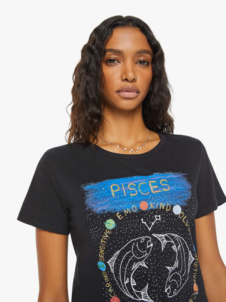 Close up view of a woman black tee features the symbol of the water sign, Pisces — two fish swimming in opposite directions.
