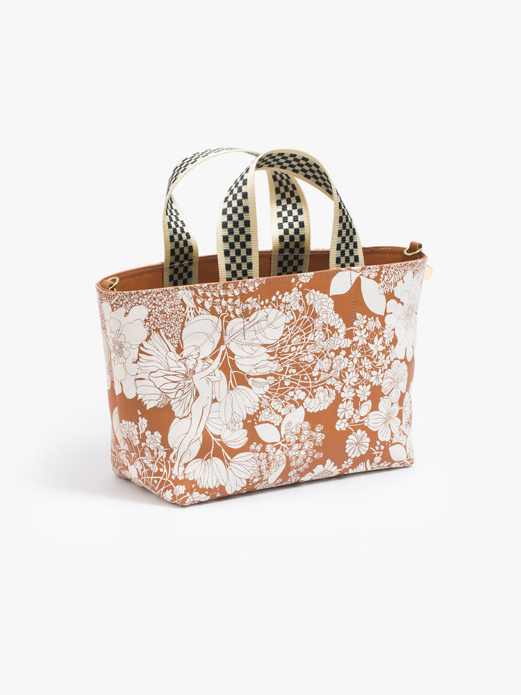 Front 3/4 view of a rectangular bag features a zip closure and checkered top handle, and is designed in French Fairy Tale, a brown and white floral print. Pair it with the Link Up strap for added versatility.