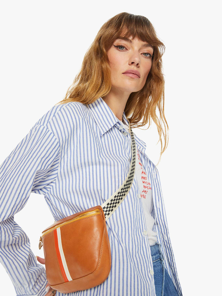 Side view on model of a waist bag is designed with a zip closure, checkered strap and white and orange stripes down the front.