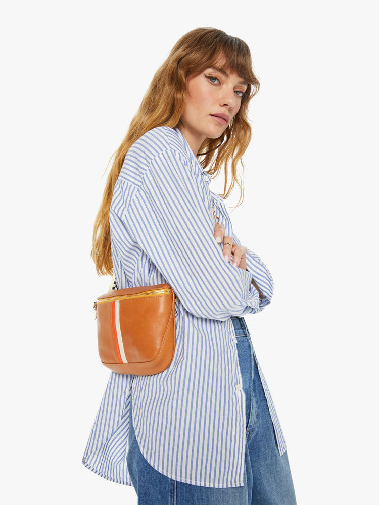 On model view of a waist bag is designed with a zip closure, checkered strap and white and orange stripes down the front.