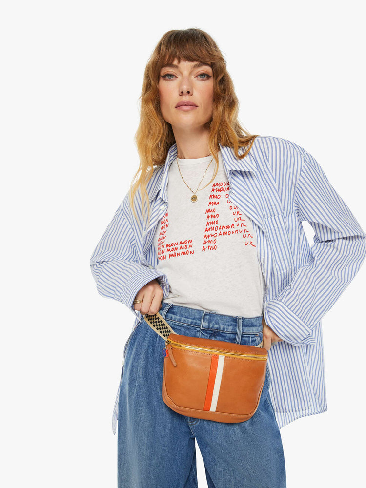 On model view of a waist bag is designed with a zip closure, checkered strap and white and orange stripes down the front.