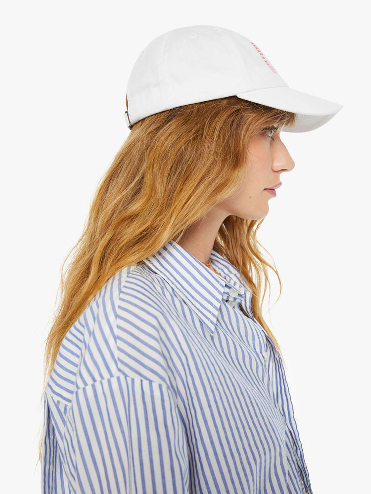 Side on model view of a woman white hat and is designed with a red text graphic on the front.