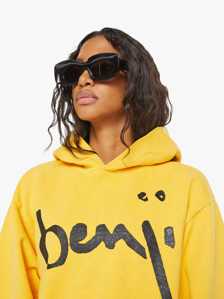 WOMEN close view of a mustard yellow patch pocket, ribbed hems and a slightly oversized sweatshirt.