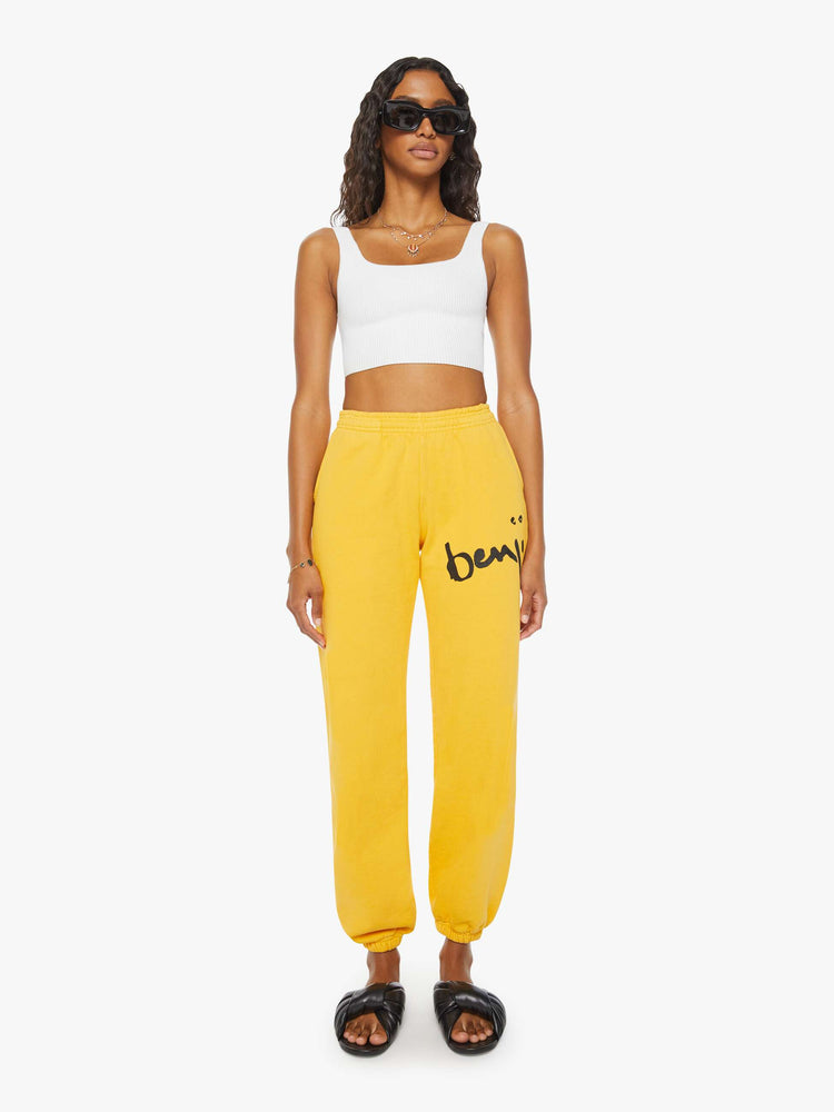 WOMEN front view of a woman mustard yellow elastic waist and cuffs sweatpants with founding fathers eyes on the back.