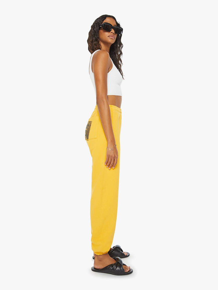WOMEN side view of a woman mustard yellow elastic waist and cuffs sweatpants with founding fathers eyes on the back.