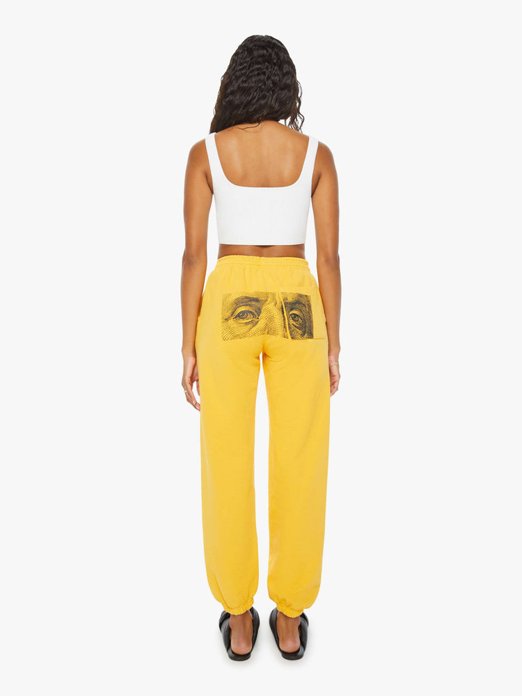 WOMEN back view of a woman mustard yellow elastic waist and cuffs sweatpants with founding fathers eyes on the back.