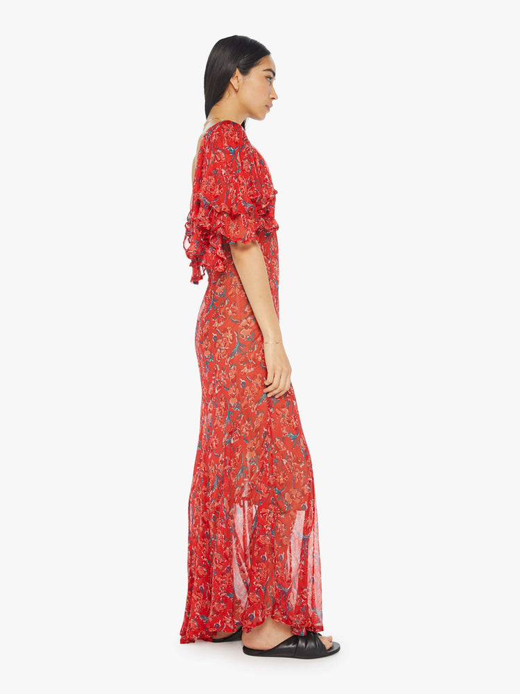 Side view of womens long dress featuring a red floral print, a deep v neck, and ruffled sleeves.