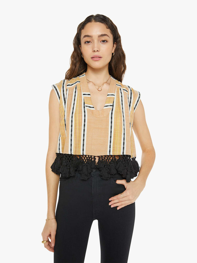 Front view of a woman wearing a yellow, striped button up top with black lace fringe at the hem.