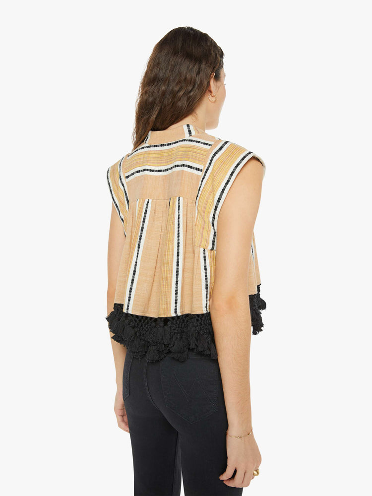 Back view of a woman wearing a yellow, striped button up top with black lace fringe at the hem