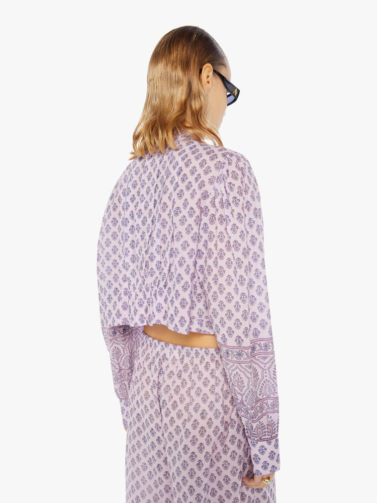Back view of a woman wearing a button down blouse with all-over purple floral print