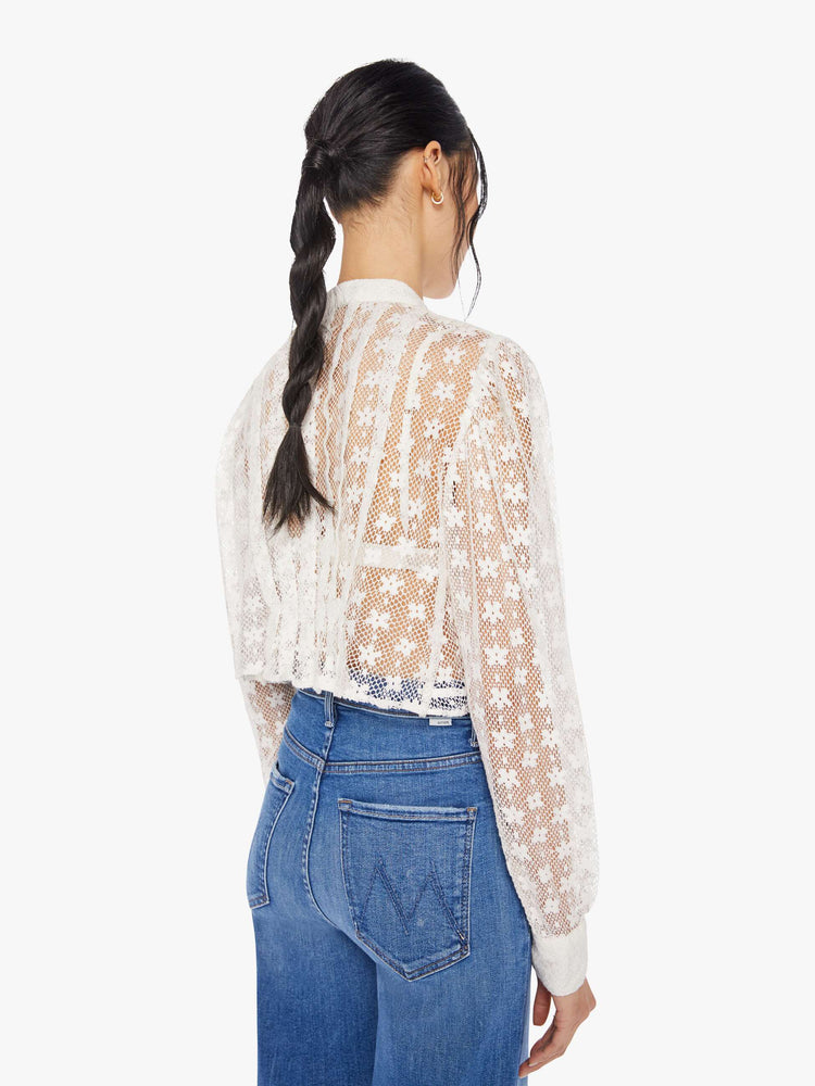 Back view of a woman wearing a white lace, floral, button up blouse with long balloon sleeves
