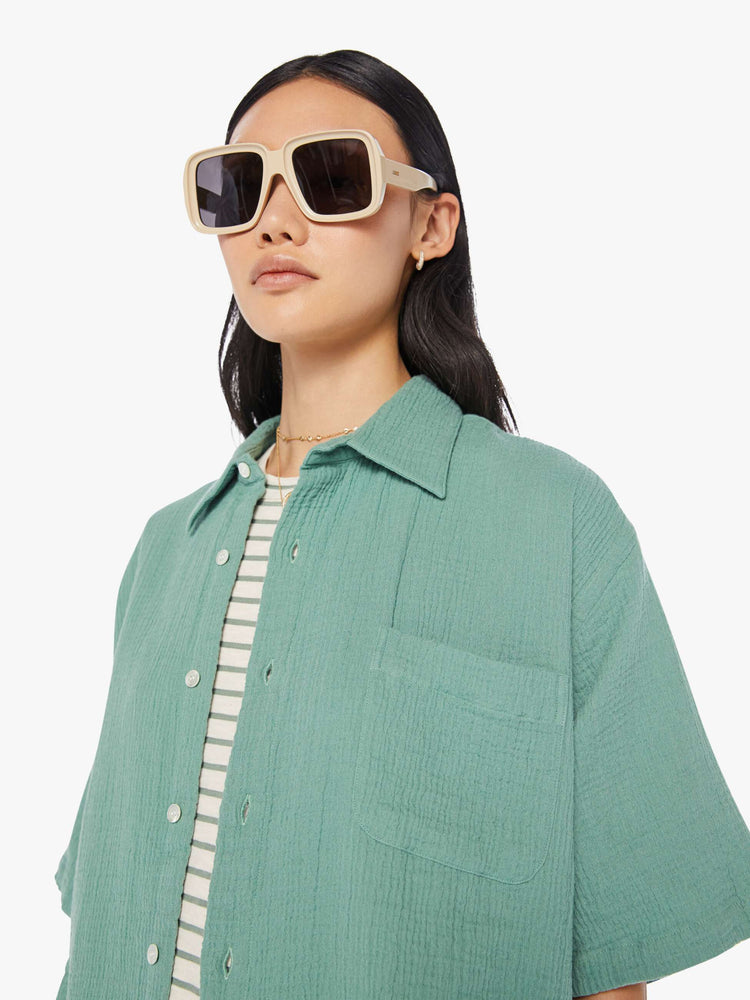 Front close up view of a womens green short sleeve button down shirt featuring an oversized fit.