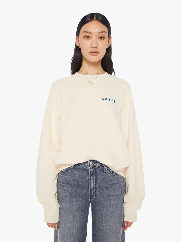 Front view of a womens ecru crew neck sweatshirt featuring an oversized fit and a logo printed on the chest pocket.