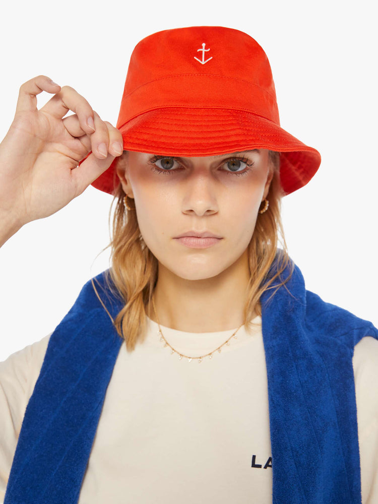 Front view of a woman wearing a red bucket hat with a white anchor embroidered on the front.