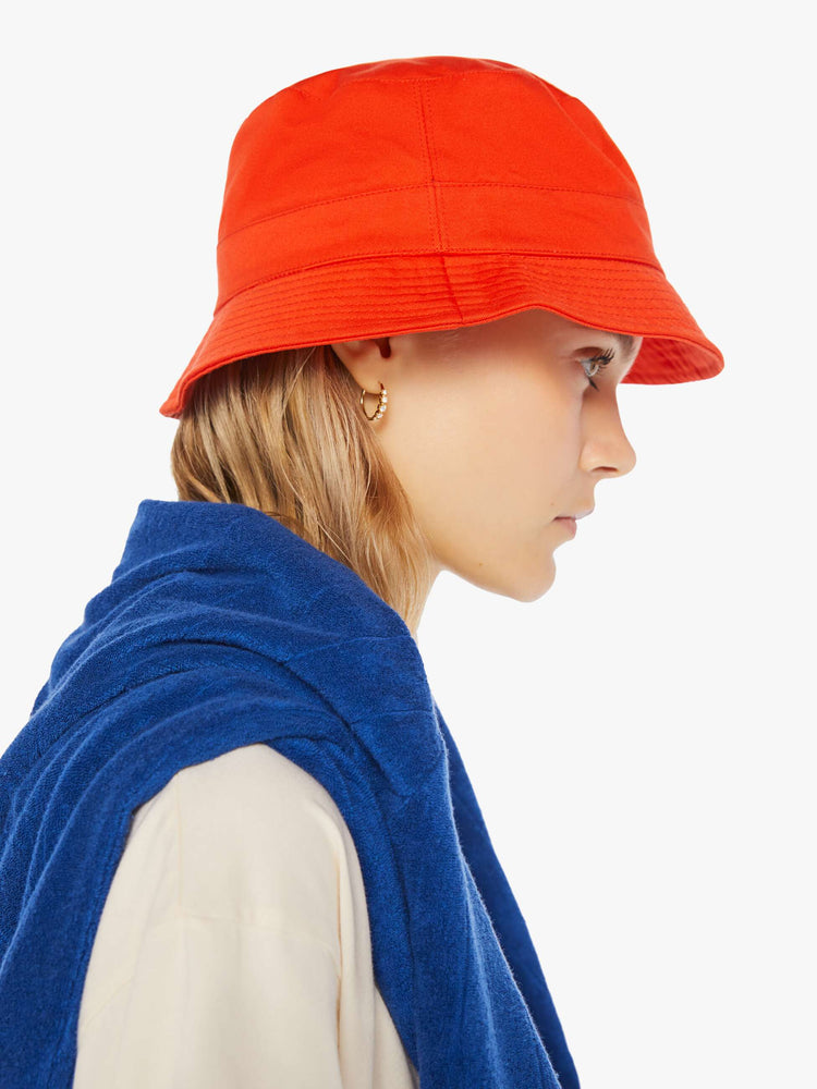 Side view of a woman wearing a red bucket hat.