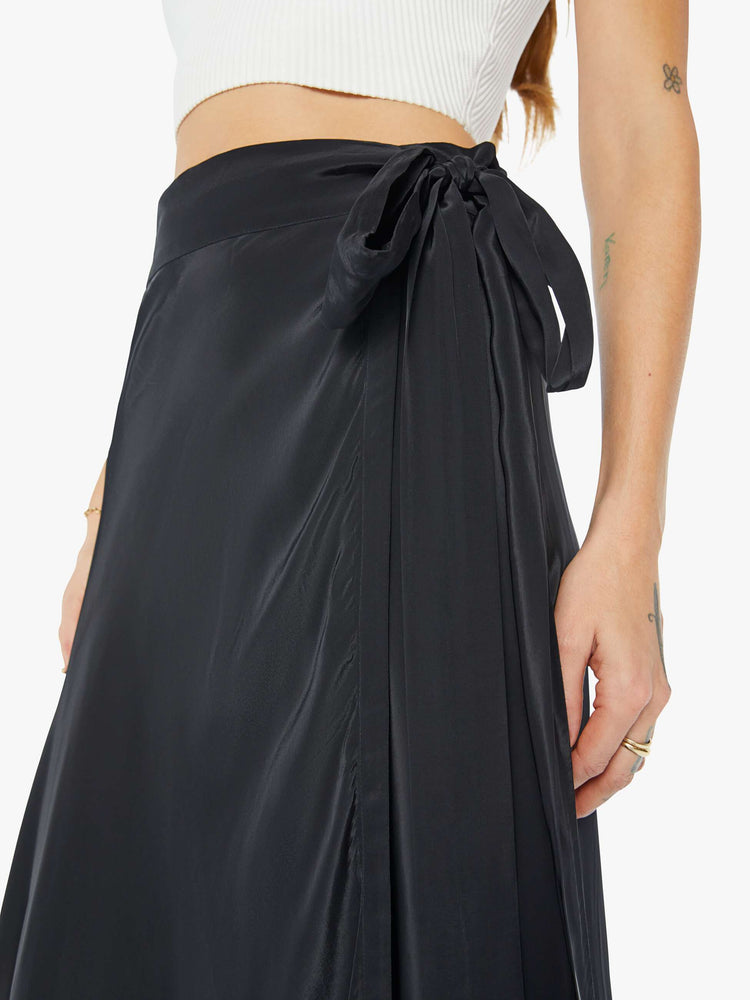 Side close up view of a womens black wrap skirt featuring a high waist.