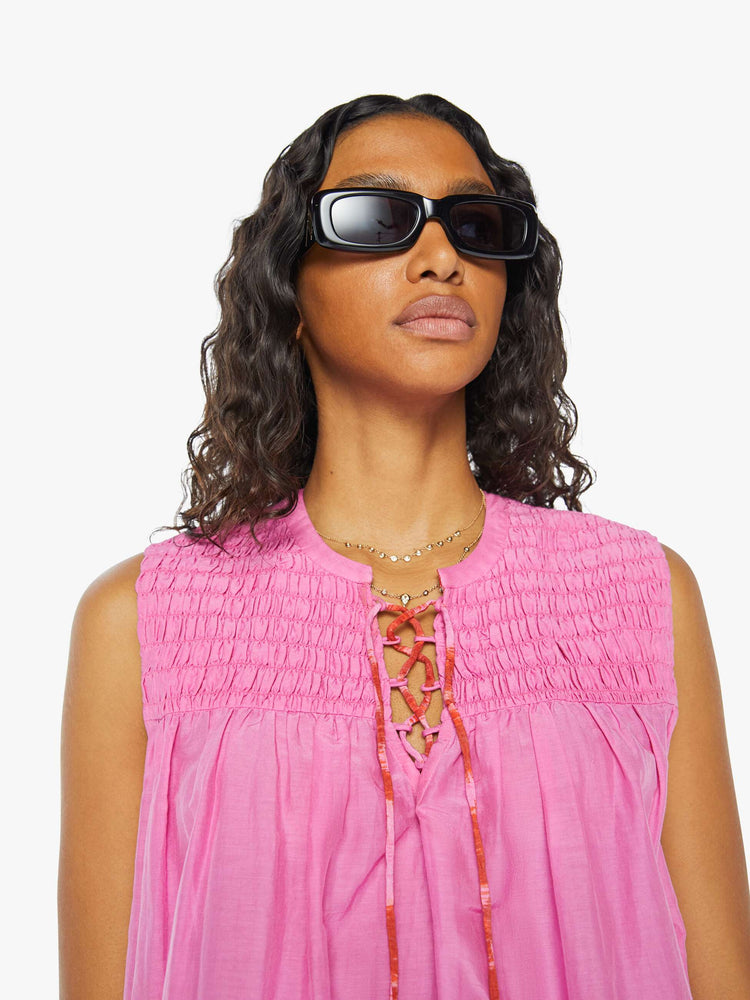 Front close up view of a womens sleeveless top featuring a v neck with tassels.
