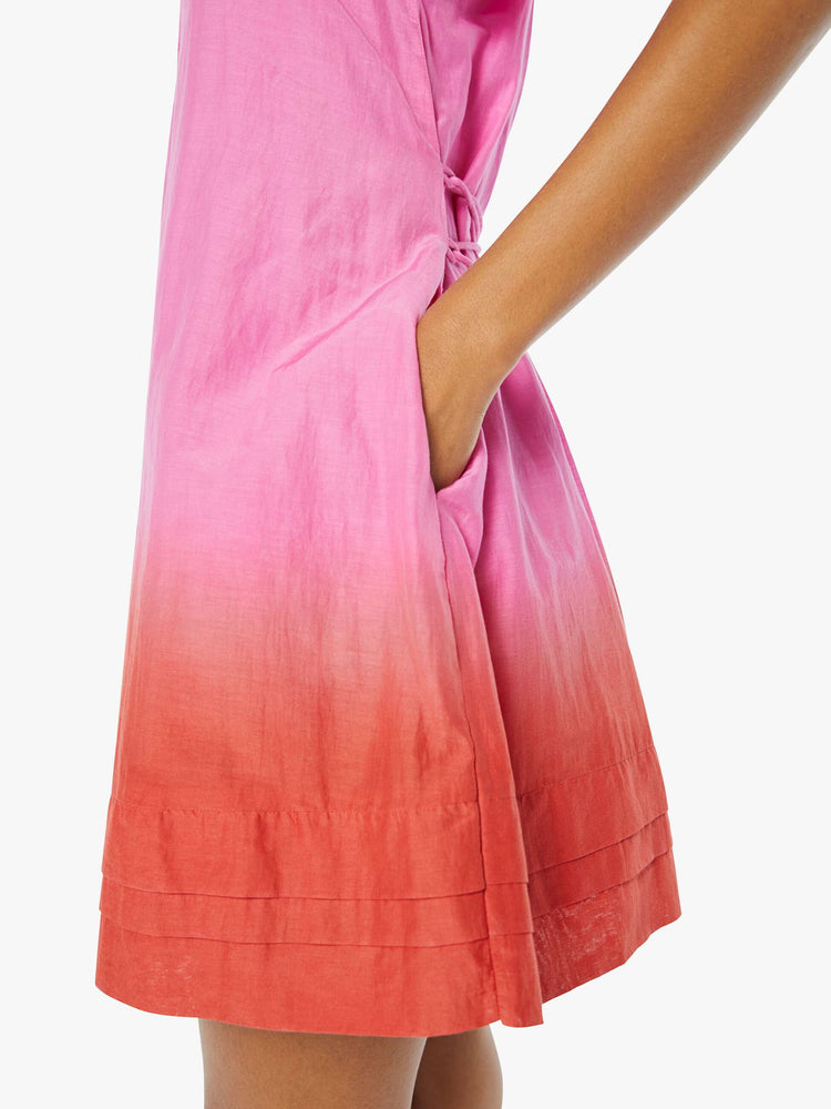 Side view of a womens short dress in a pink to red ombre, featuring side pockets.