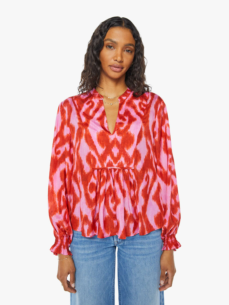 Front view of a womens long sleeve blouse featuring a red and pink print and a center tie.