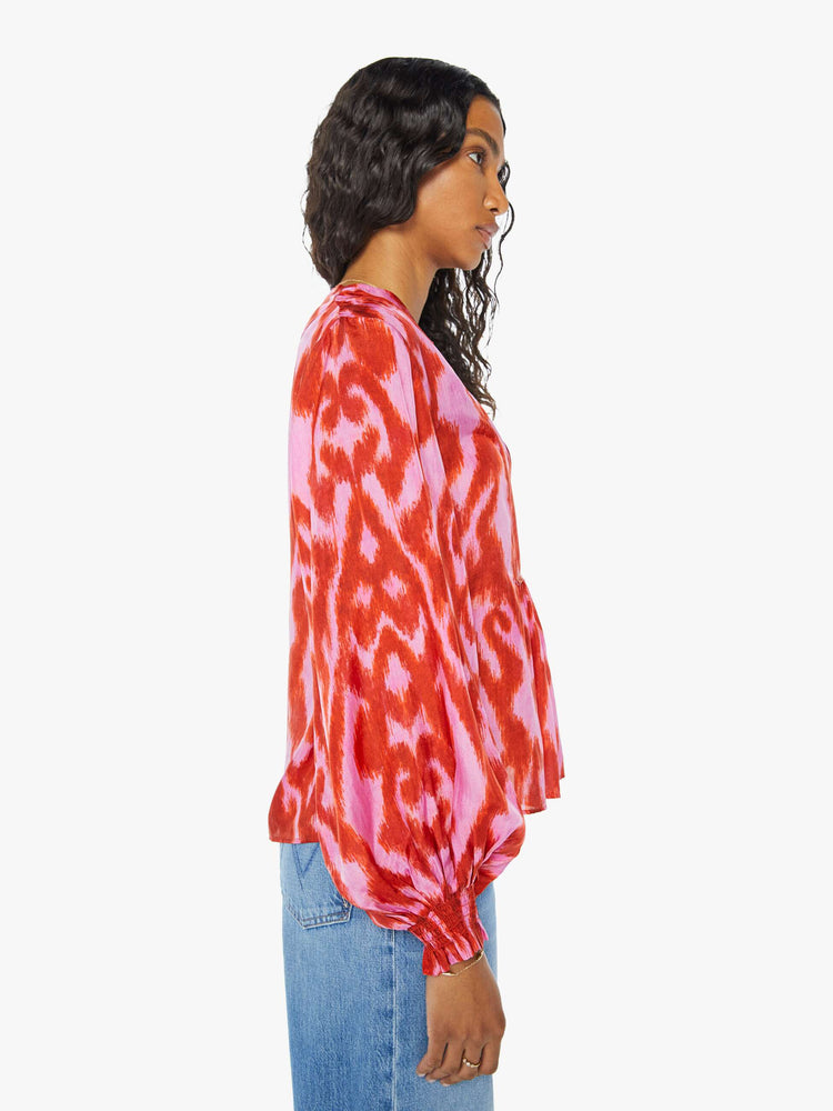 Side view of a womens long sleeve blouse featuring a red and pink print and a center tie.