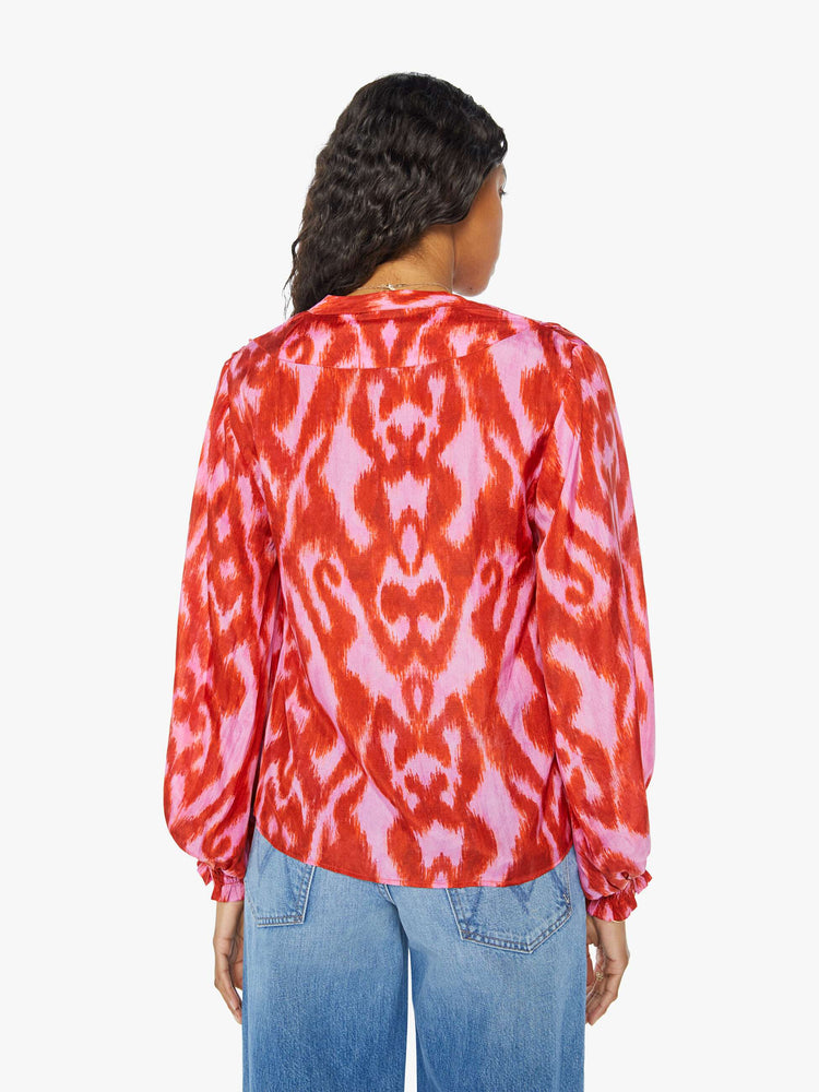 Back view of a womens long sleeve blouse featuring a red and pink print and a center tie.
