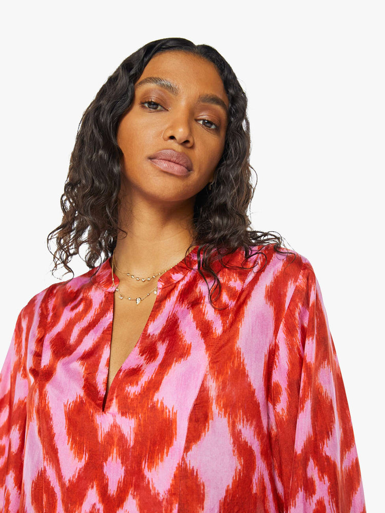 Front close up view of a womens long sleeve blouse featuring a red and pink print and a center tie.