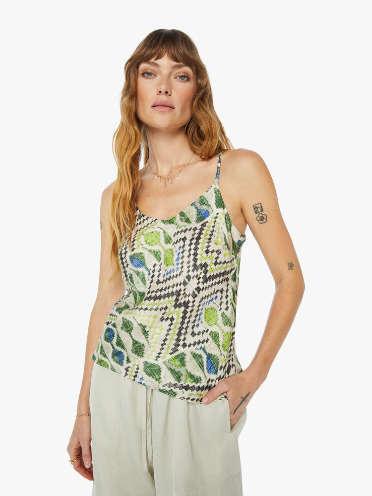 A front view of a woman wearing a spaghetti strap top featuring a green multi color pattern.