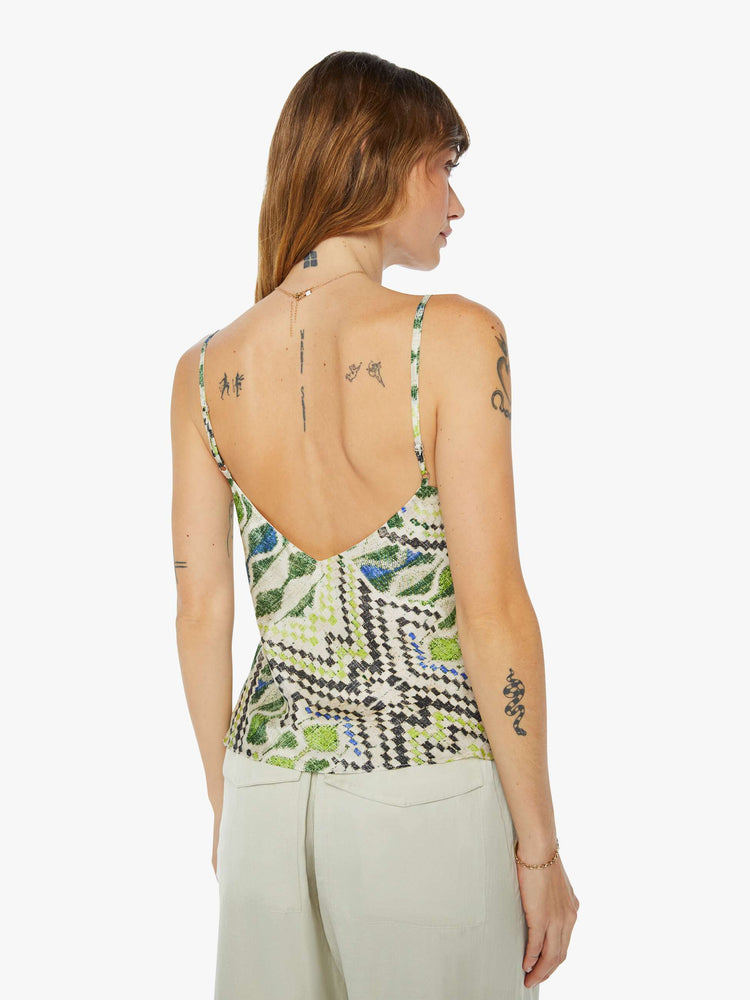 A back view of a woman wearing a spaghetti strap top featuring a green multi color pattern.
