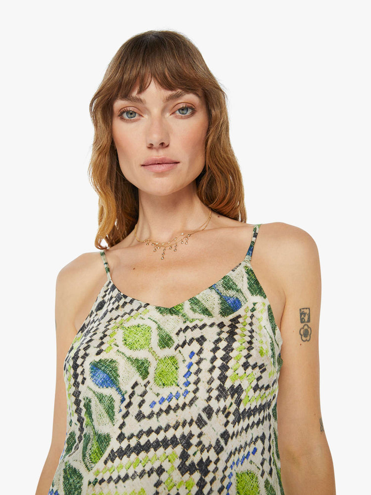 A front close up view of a woman wearing a spaghetti strap top featuring a green multi color pattern.