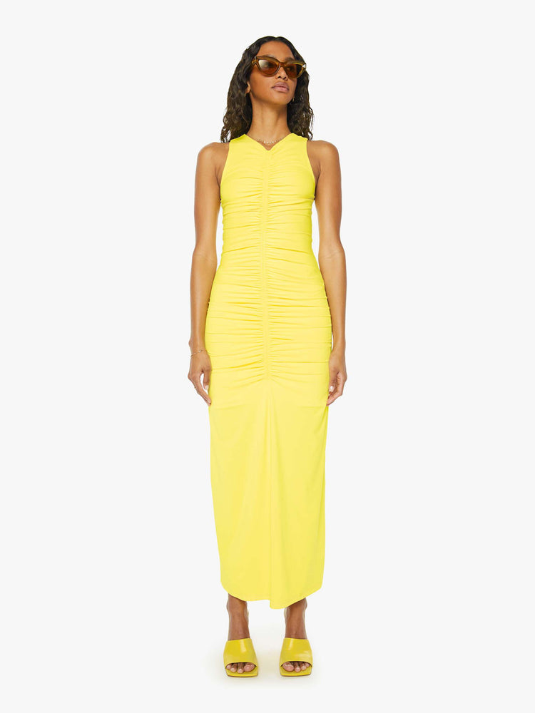 Front view of a woman wearing a bright yellow sleeveless dress with a small v-neck, a long gathered seam down the front, and an ankle length hem.