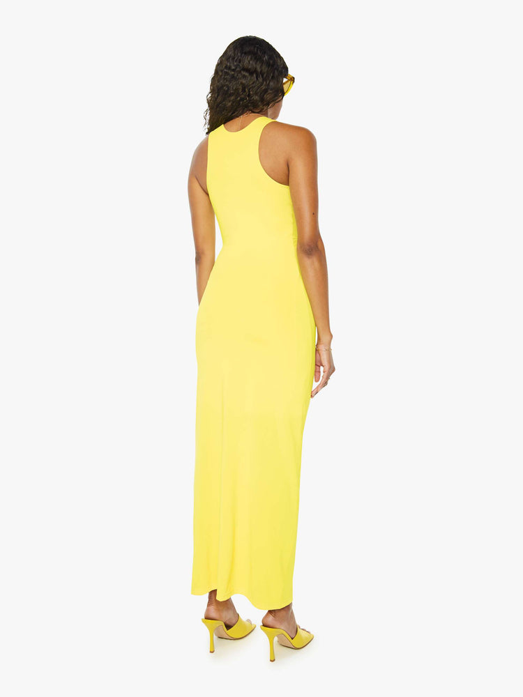 Back view of a woman wearing a bright yellow sleeveless dress with a racer back and an ankle length hem.