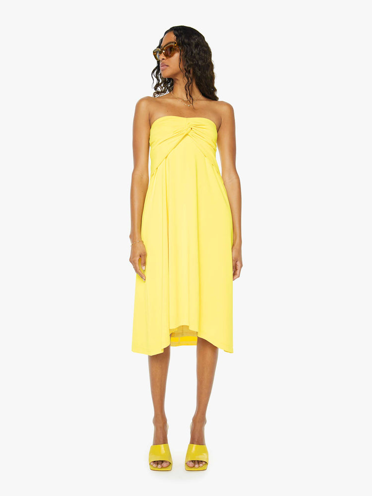 A front view of a woman wearing a bright yellow skirt with a flowy fit as a sleeveless dress.