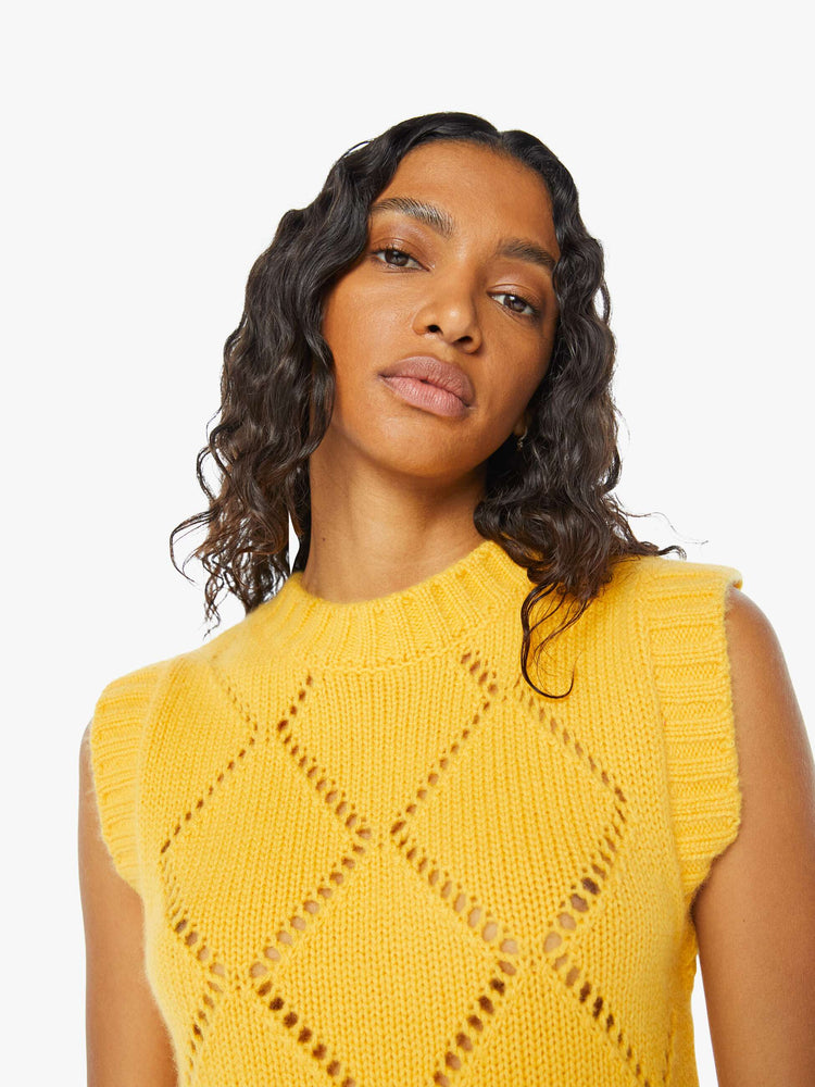 Front close up view of woman wearing a yellow knit sweater vest, featuring a diamond pattern.