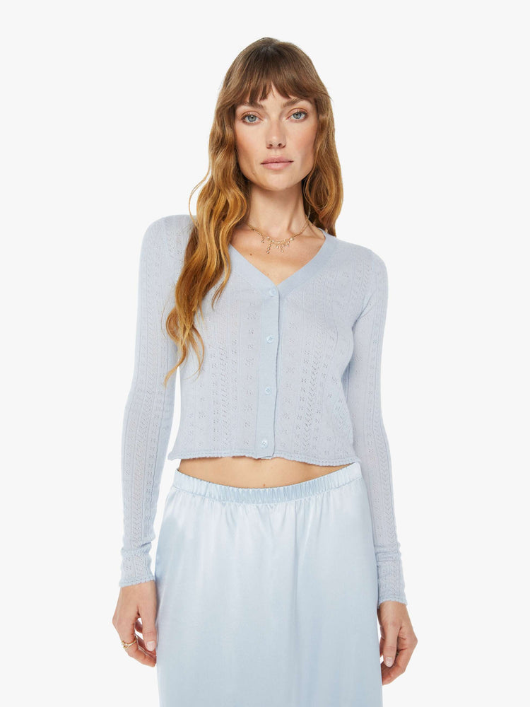 A front view of a woman wearing a light blue skirt with a light blue knit cardigan with a fitted and cropped fit.