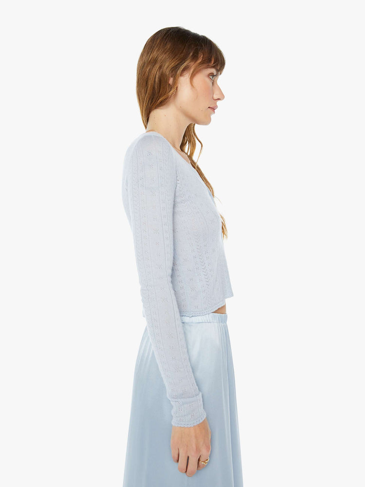 A side view of a woman wearing a light blue skirt with a light blue knit cardigan with a fitted and cropped fit.