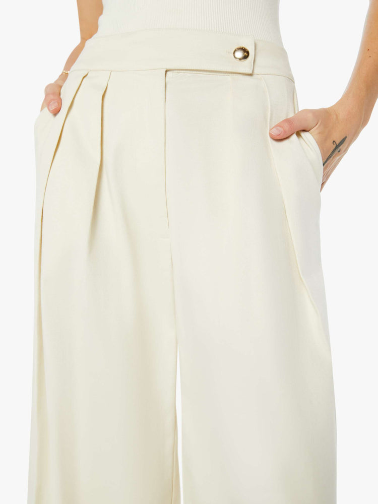 Front close up view of a womens off white pant featuring a high rise, a pleated wide leg, and long inseam.